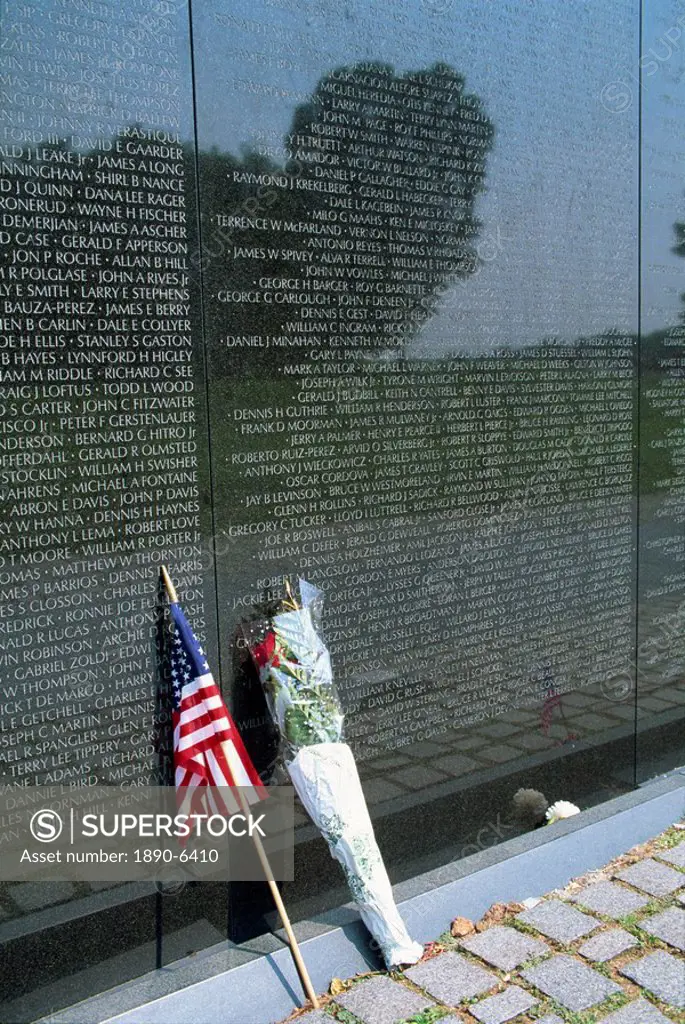 Flag and flowers against the list of names on the Vietnam Veterans Memorial in Washington D.C., United States of America, North America