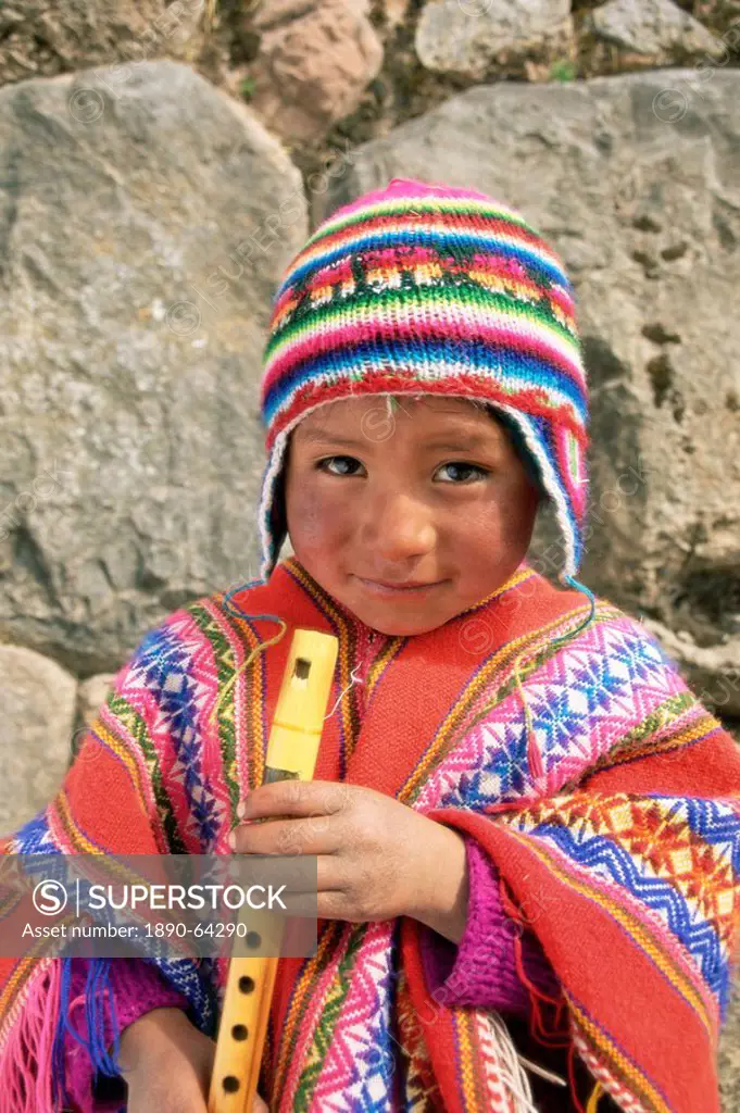 Portrait of a Peruvian boy in a knitted hat, playing the flute, near Cuzco, Peru, South America