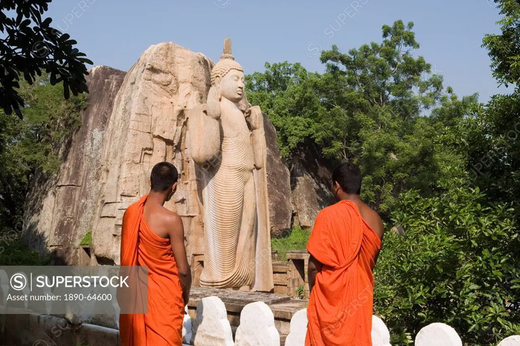 Buddhist monks in front of the giant standing statue of the Buddha dating from the 5th century, Aukana, Sri Lanka, Asia