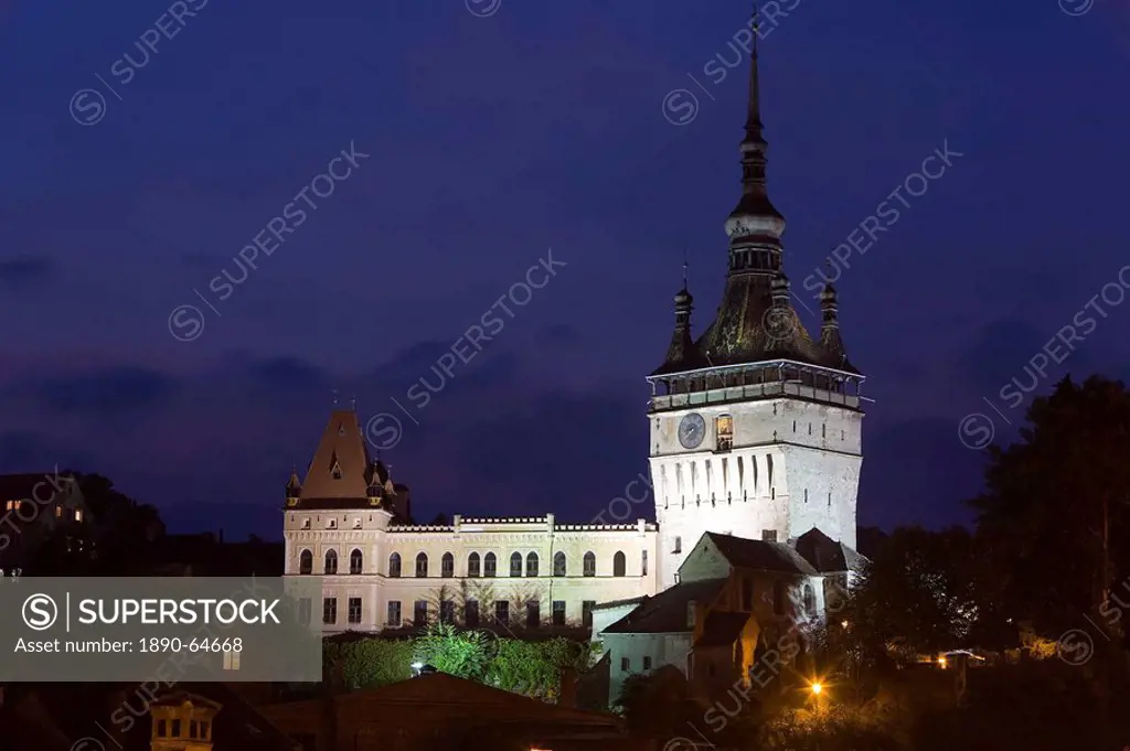 Clock tower Turnul cu Ceas, illuminated at dusk, formerly the main entrance to the fortified city, in the medieval old town or citadel, Sighisoara, UN...