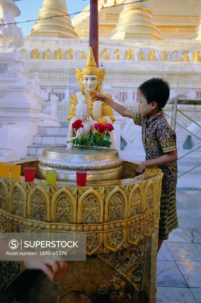 A boy places offerings to the Buddha, Shwedagon Paya Shwe Dagon pagoda, Yangon Rangoon, Myanmar Burma, Asia