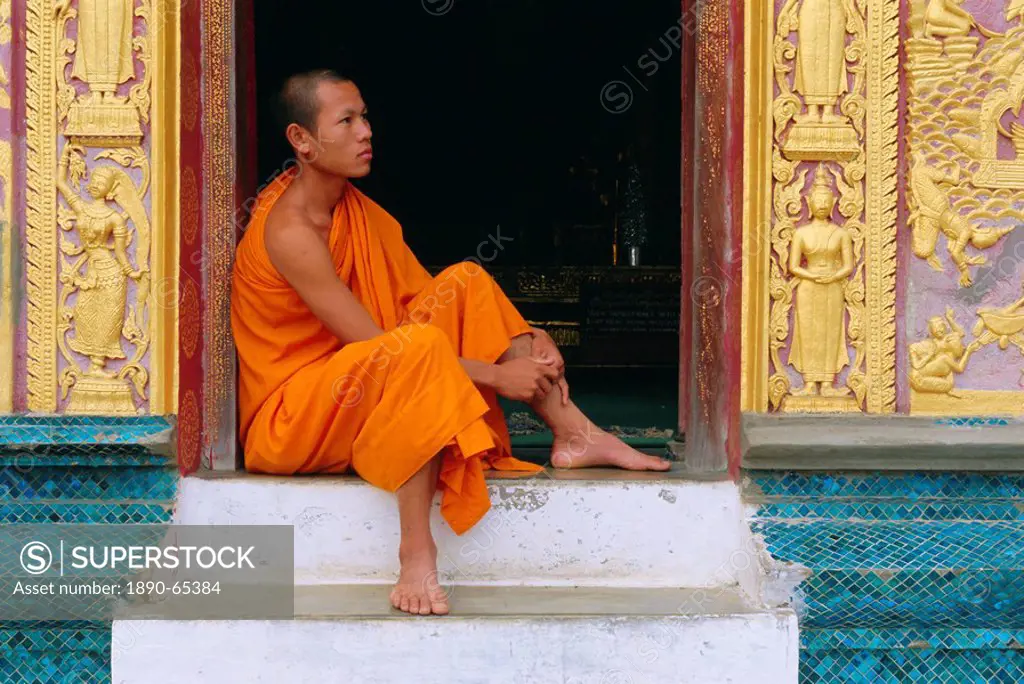 Monk sitting in temple doorway, Wat Xieng Thong, Luang Prabang, Laos