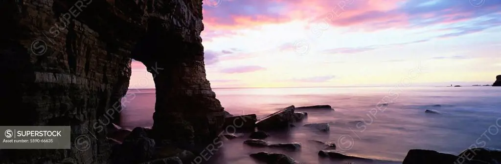 Dawn view over North Sea from beach at Marsden Bay, showing natural rock arch in Marsden Rock, South Shields, Tyne and Wear, England, United Kingdom, ...