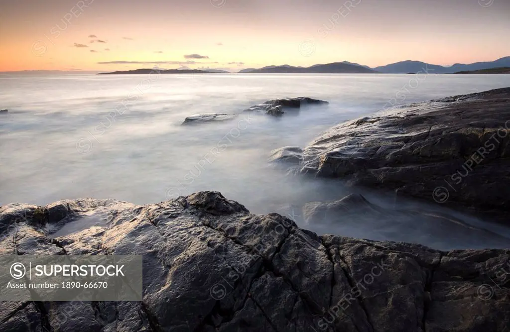 Dusk view across open water towards Taransay and North Harris from the rocky shore at Borve, Isle of Harris, Outer Hebrides, Scotland, United Kingdom,...