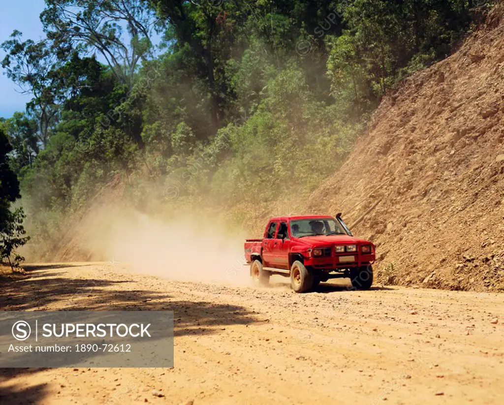 A red 4x4 pick_up on the dusty Bloomfield Track, Cape Tribulation National Park, Queensland, Australia