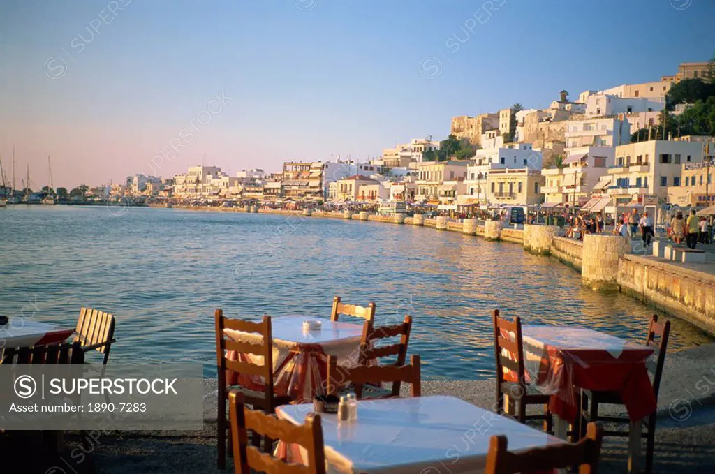 Tables and chairs in cafe on the harbour with the waterfront in the background, on Naxos, Cyclades Islands, Greek Islands, Greece, Europe