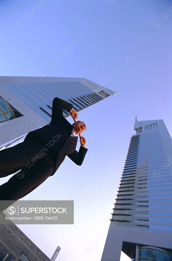 Business man with fingers in his ears in front of tall buildings