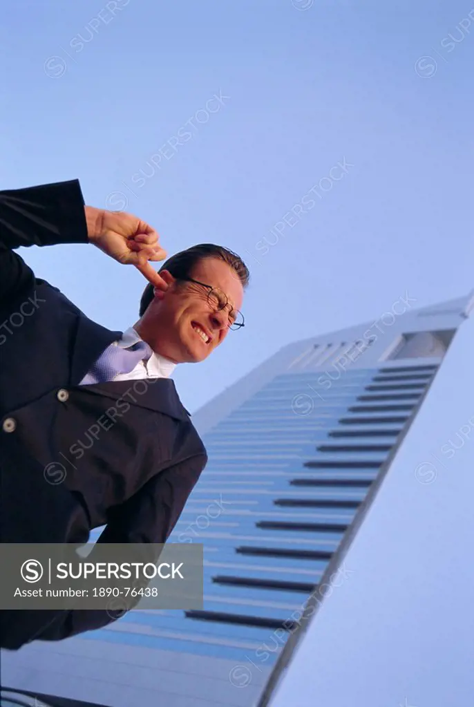 Business man with finger in one ear, wearing glasses, outdoors