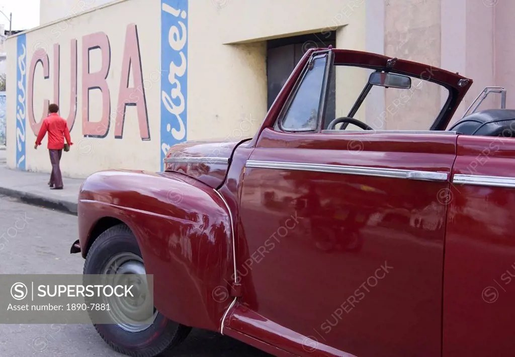 A vintage car near a ´Viva Cuba´ sign painted on a wall in cental Havana, Cuba, West Indies, Central America