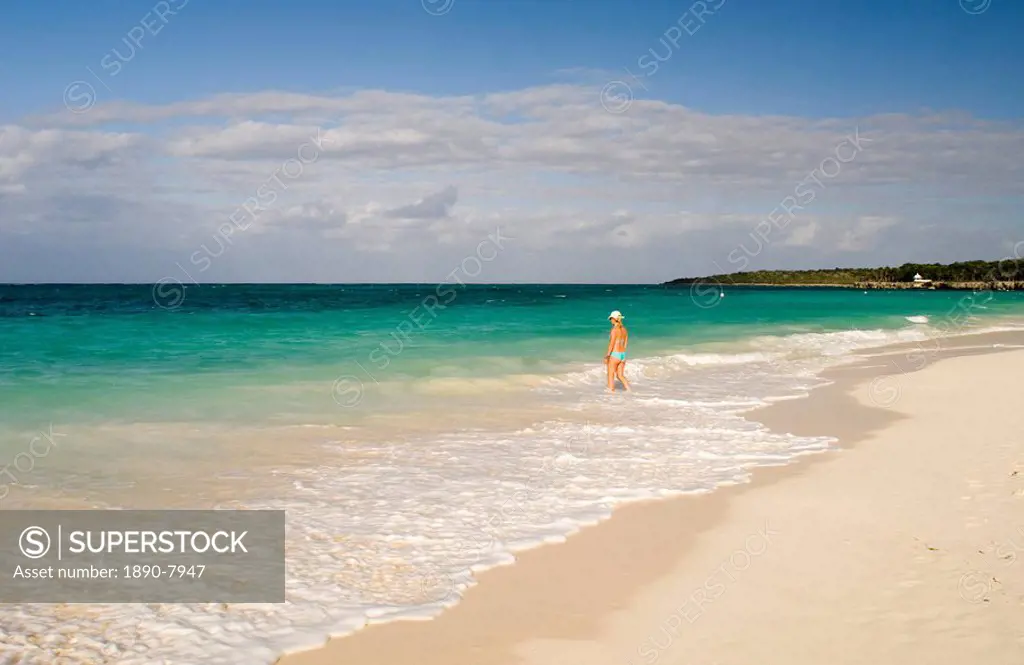 A woman walking in the surf at Playa Esmeralda, Carretera Guardalavarca, Cuba, West Indies, Central America
