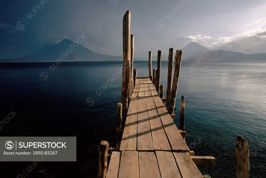Wooden jetty and volcanoes in the distance, Lago Atitlan Lake Atitlan, Guatemala, Central America