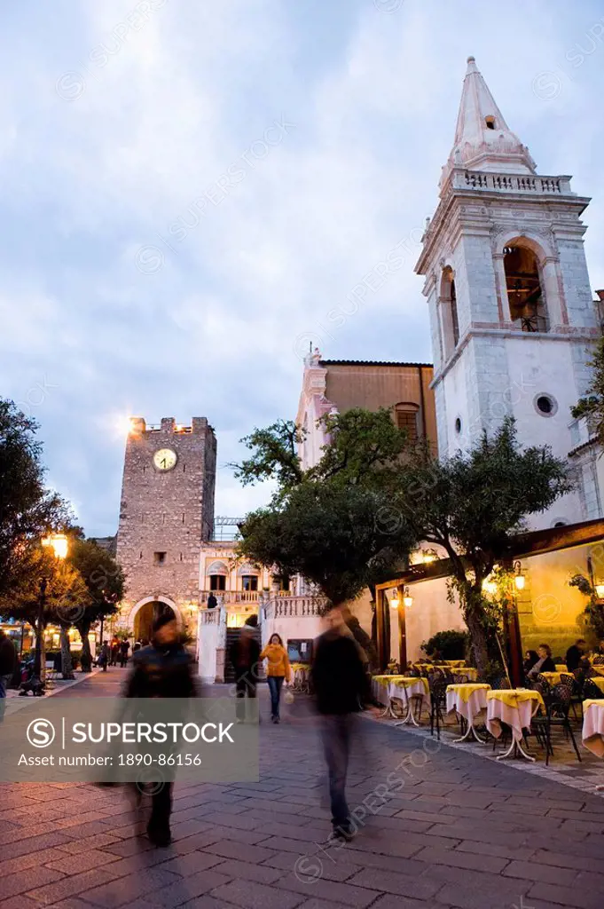 People strolling in Piazza IX Aprile in the evening, with the Torre dell Orologio and San Giuseppe church, Taormina, Sicily, Italy, Europe