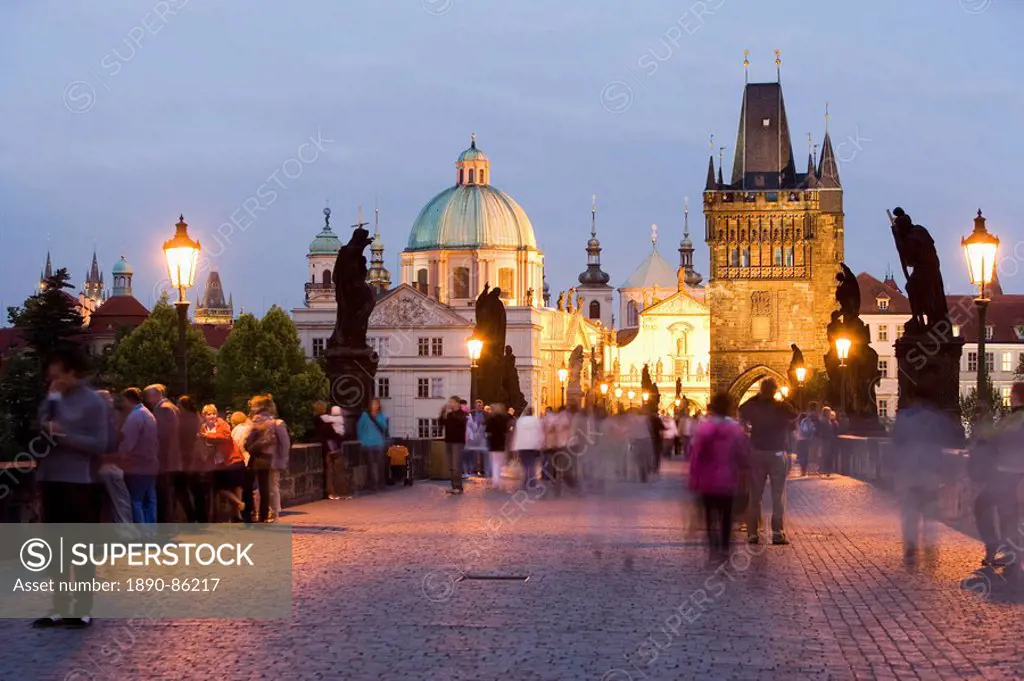 Statues and crowds on the Charles Bridge, with the dome of the Church of St. Francis and the Old Town Bridge Tower beyond, evening light, Old Town, Pr...