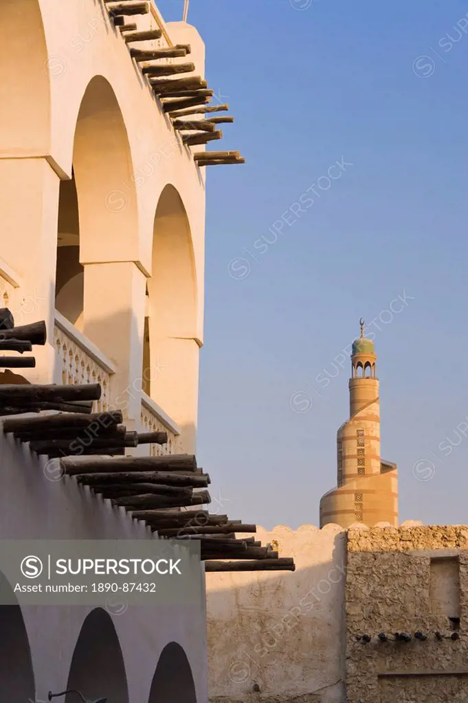 The restored Souq Waqif with mud rendered shops and exposed timber beams and the spiral mosque of the Kassem Darwish Fakhroo Islamic Centre based on t...