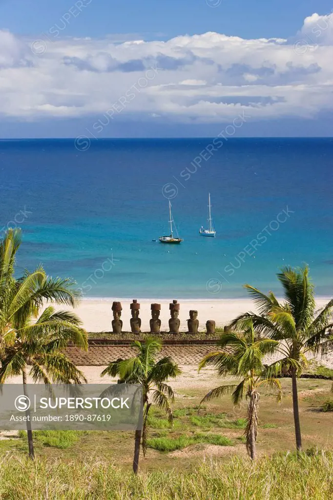 Anakena beach, yachts moored in front of the monolithic giant stone Moai statues of Ahu Nau Nau, four of which have topknots, Rapa Nui Easter Island, ...