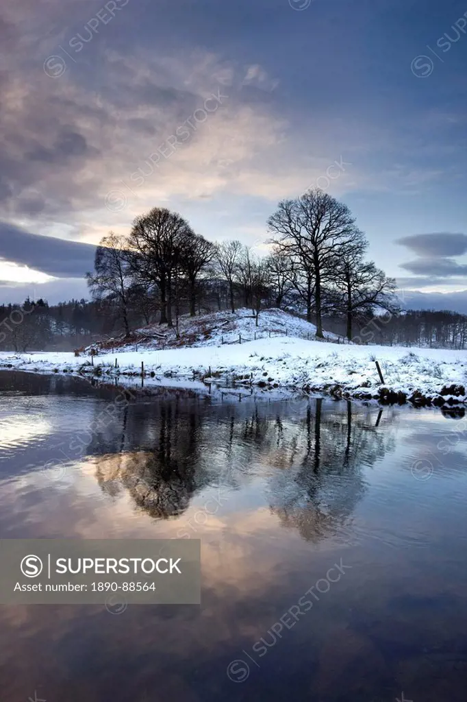 Winter view of River Brathay at dawn, under snow with reflections, near Elterwater Village, Ambleside, Lake District National Park, Cumbria, England, ...