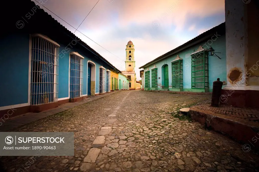 Deserted cobbled street looking towards the bell tower of the Inglesia y Convento de San Francisco off Plaza Major, Trinidad, Cuba, West Indies, Centr...