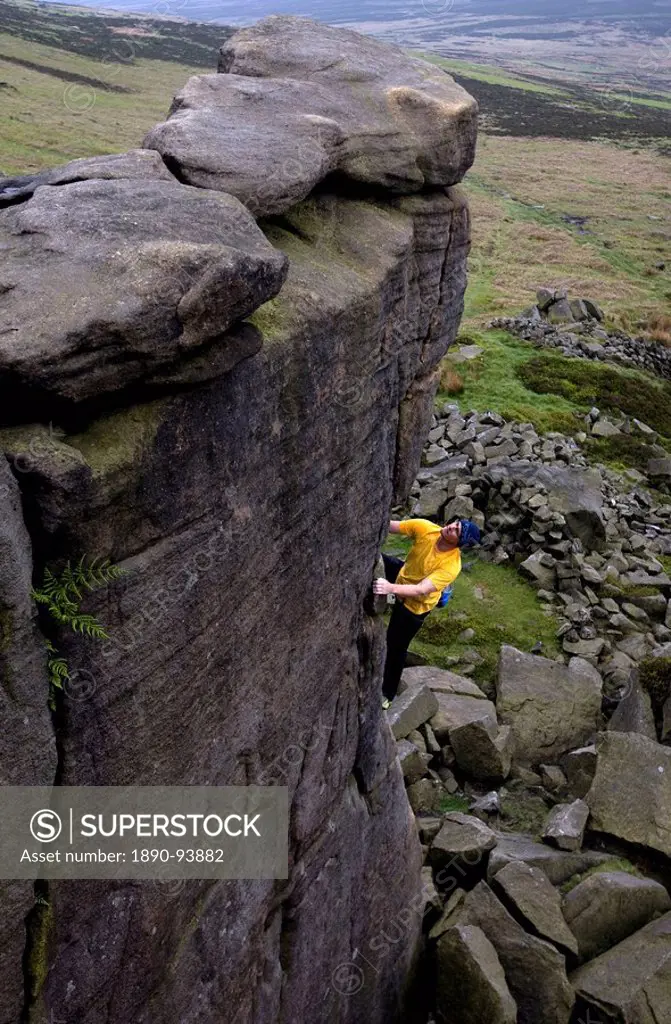 Climber makes a solo ascent of one of the thousands of classic outcrop climbs on the popular cliff of Stanage Edge, near Hathersage, Peak District, De...