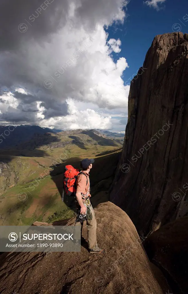 A climber looks up towards the 800 metre Tsaranoro Be Big Tsaranoro Monolith, Andringitra National Park, Southern Madagascar, Africa