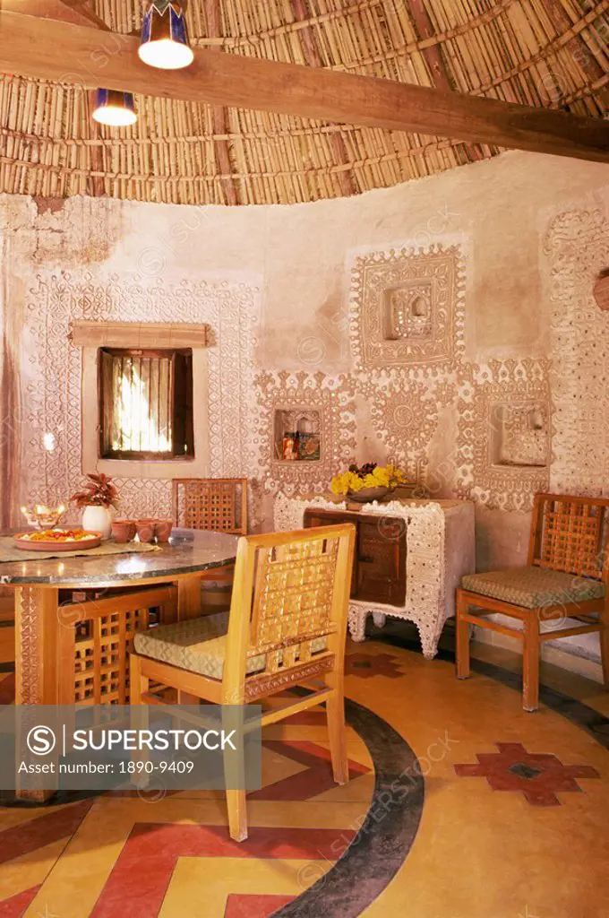 Raised mud reliefs inlaid with mirror on the walls of dining area in modern home in traditional tribal Rabari round mud hut, Bunga style, near Ahmedab...