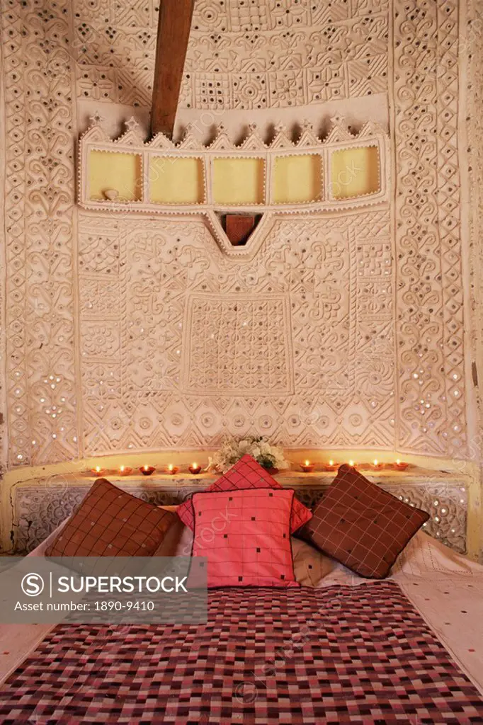 Raised mud reliefs inlaid with mirror on the walls of bedroom in modern home in traditional tribal Rabari round mud hut, Bunga style, near Ahmedabad, ...