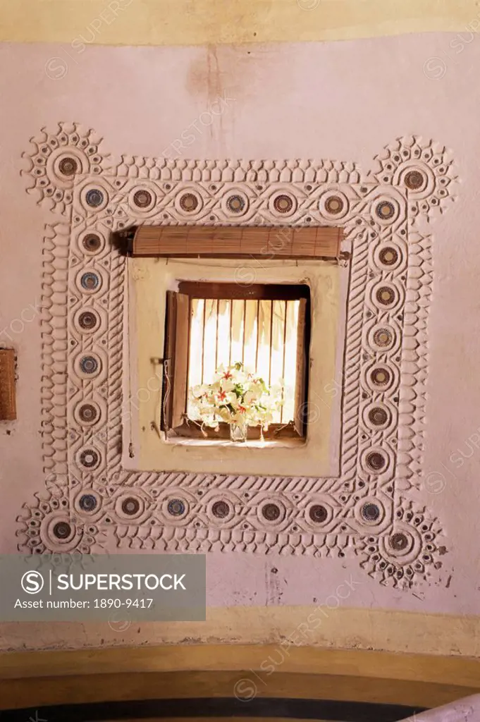 Raised mud reliefs inlaid with mirror on the walls of modern home in traditional tribal Rabari round mud hut, Bunga style, near Ahmedabad, Gujarat sta...