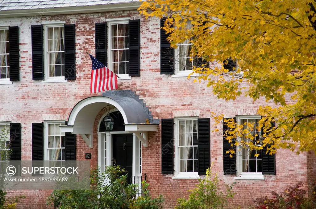 An old brick house displaying an American flag and surrounded by autumn foliage in Townshend, Vermont, New England, United States of America, North Am...