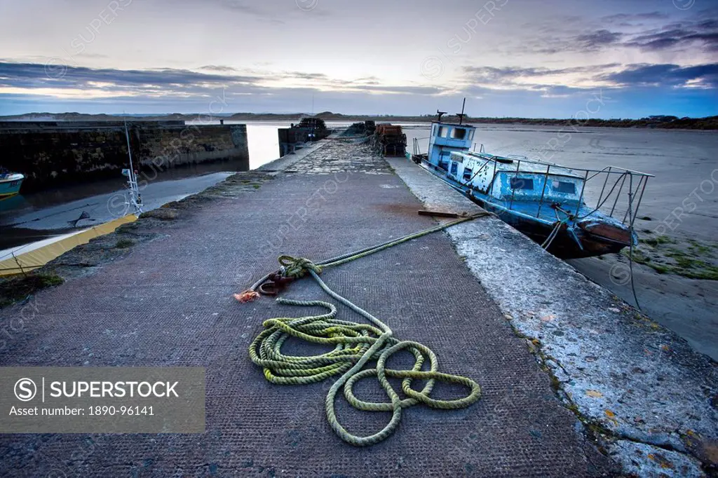 Beadnell Harbour at dusk showing old rope coiled on harbourside and dilapidated fishing boat, Beadnell, Northumberland, England, United Kingdom, Europ...