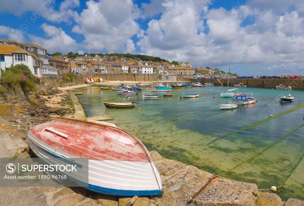 Small unturned boat on the quay and small boats in the enclosed harbour at Mousehole, Cornwall, England, United Kingdom, Europe