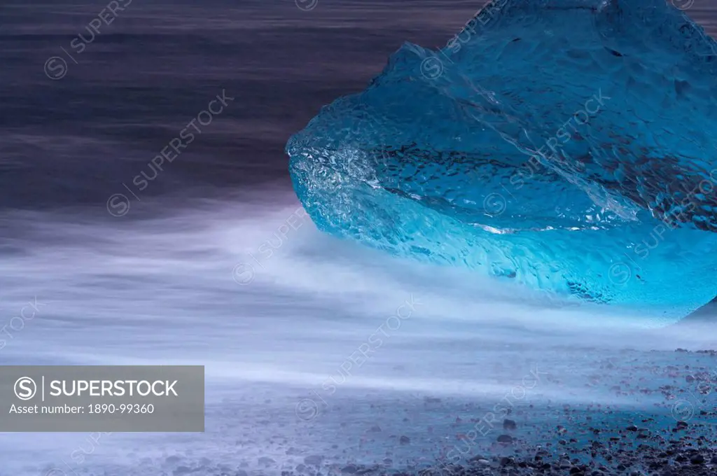 Translucent blue iceberg washed ashore on Breidamerkursandur black sands, near Jokulsarlon glacial lagoon, East Iceland, Polar Regions