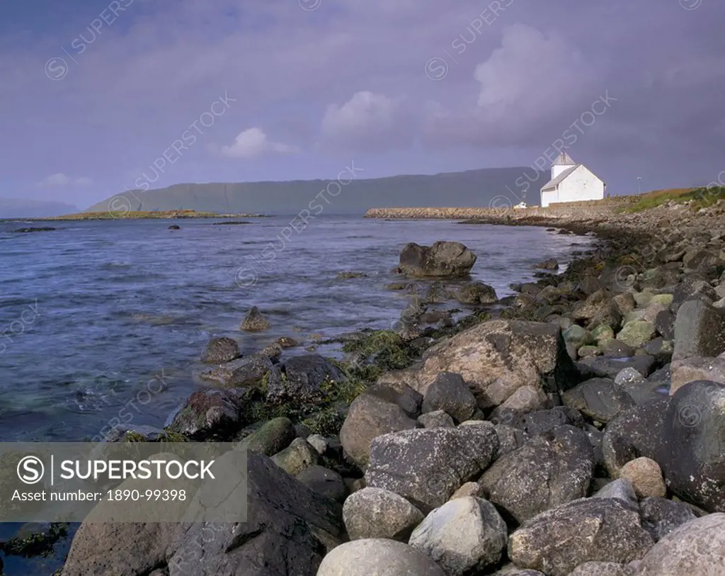 Kirkjubour, church and rocky shoreline, Hestur in the distance, Streymoy, Faroe Islands Faroes, Denmark, Europe