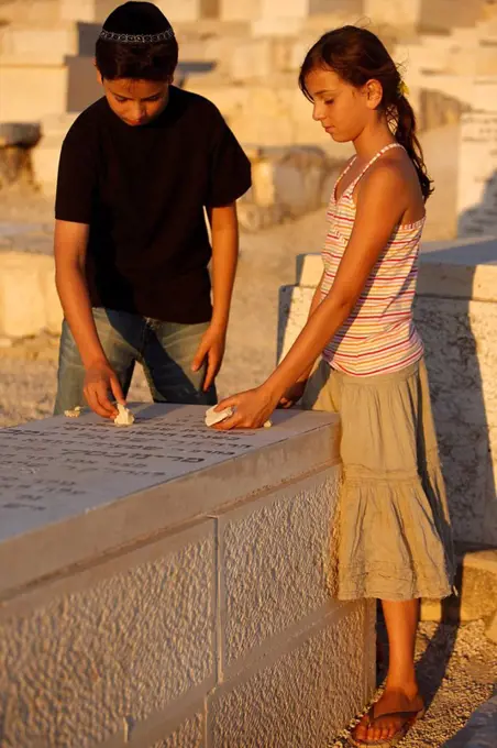 Brother and sister placing stones on a grave in the Mount of Olives Jewish cemetery, Jerusalem, Israel, Middle East