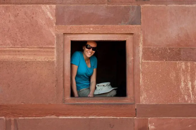 A tourist peeks out from one the windows within the Fatehpur Sikri temple complex, Uttar Pradesh, India, Asia