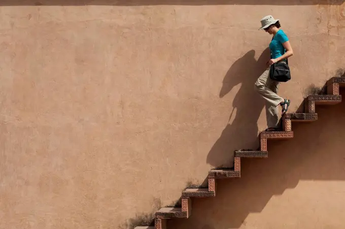 A tourist climbs downs some exposed steps within the Fatehpur Sikri temple complex, Uttar Pradesh, India, Asia