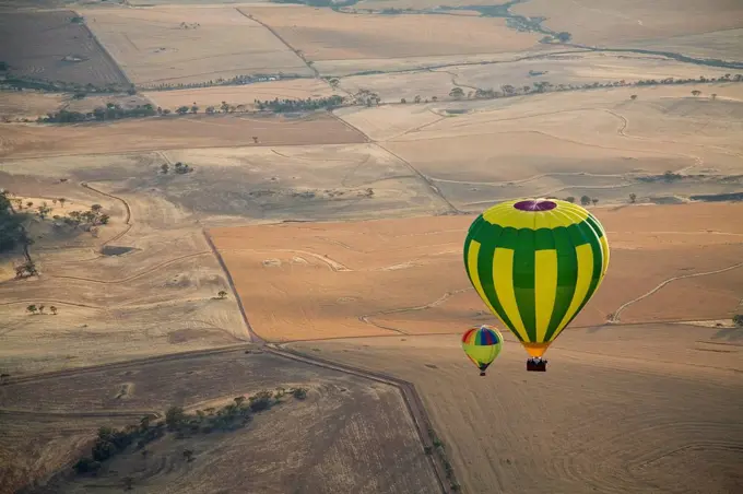 Aerial view of two hot air balloons floating over brown countryside near Northam in Western Australia, Australia, Pacific