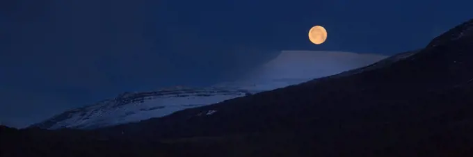 Panorama of full moon above snow covered mountains, Iceland, Polar Regions
