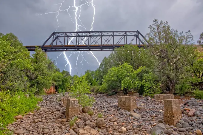 Lightning from a monsoon storm striking behind an old railroad trestle bridge that spans Bear Canyon near Perkinsville, Arizona, United States of America, North America