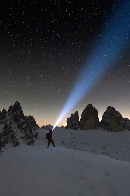 Hiker with head torch admiring stars on Monte Paterno and Tre Cime di Lavaredo, Sesto Dolomites, South Tyrol, Italy, Europe