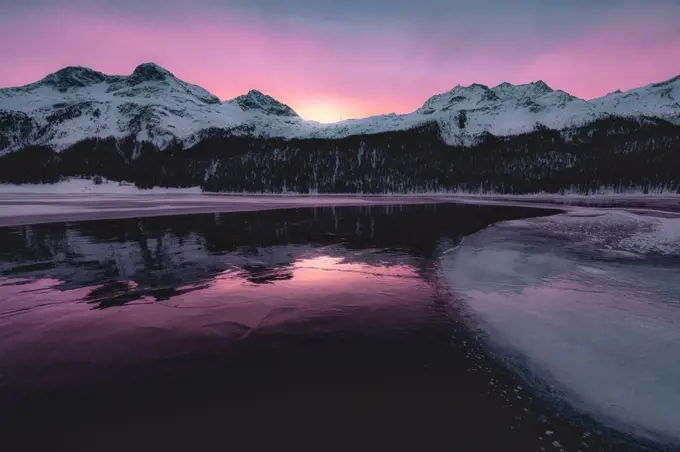 Colorful sky at sunrise on snowcapped mountains and frozen Lake Silvaplana, Maloja, Engadine, Graubunden canton, Switzerland, Europe