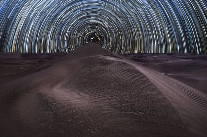 Concentric circumpolar star trail above sand dunes in the Rub al Khali desert, Oman, Middle East