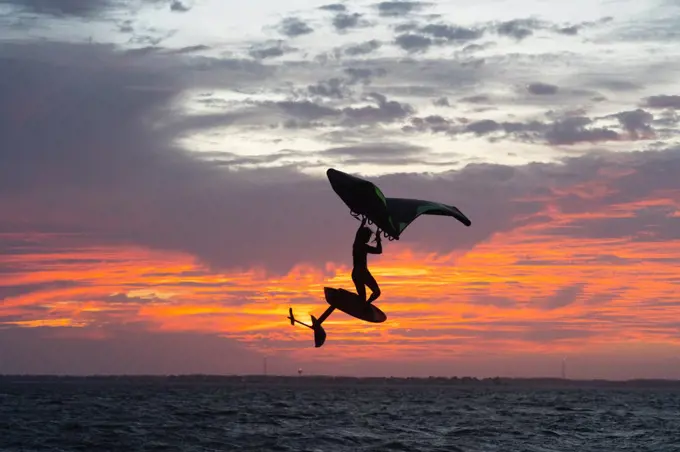 Pro surfer James Jenkins jumps his wing surfer at sunset over the Pamlico Sound at Nags Head, North Carolina, United States of America, North America