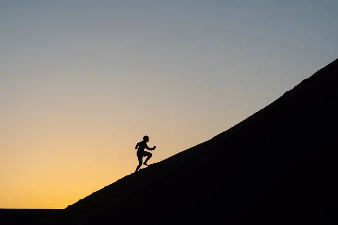 Silhouette of a man running up a sand dune in Nags Head, North Carolina, United States of America, North America