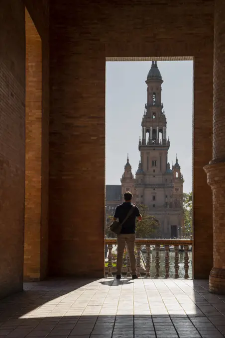 Man enjoying the view of Plaza de Espana, framed through an archway, Seville, Andalusia, Spain