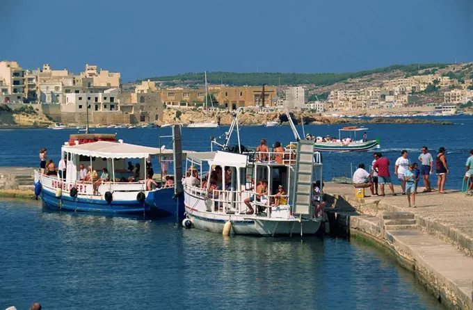 Tourists boarding boats from a jetty in St. Pauls Bay, Malta, Mediterranean, Europe