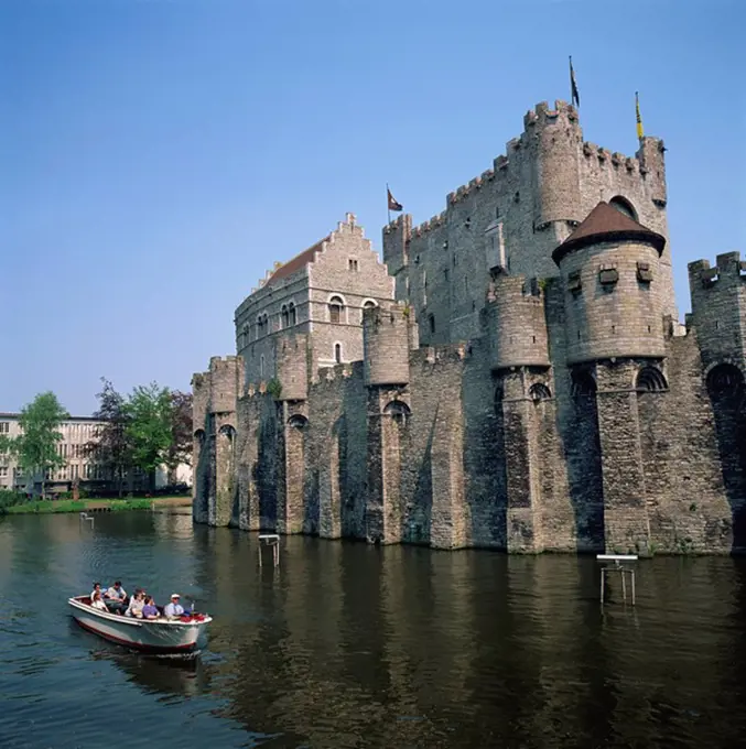Small tourist boat passing the Castle of the Counts of Flanders in the city of Ghent, Belgium, Europe