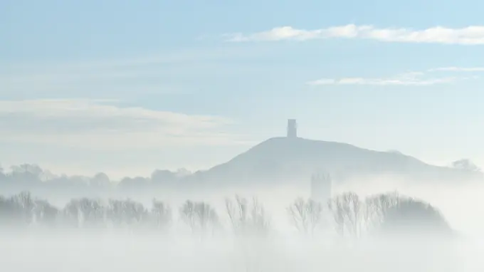 St. Michael's Tower on Glastonbury Tor above the tower of St. John the Baptist's Church on a misty morning in winter, Glastonbury, Somerset, England, United Kingdom, Europe