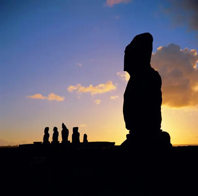 Silhouette of Ahu Tahai in foreground and behind the five moai statues of Ahu Vai Uri, Easter Island, Chile