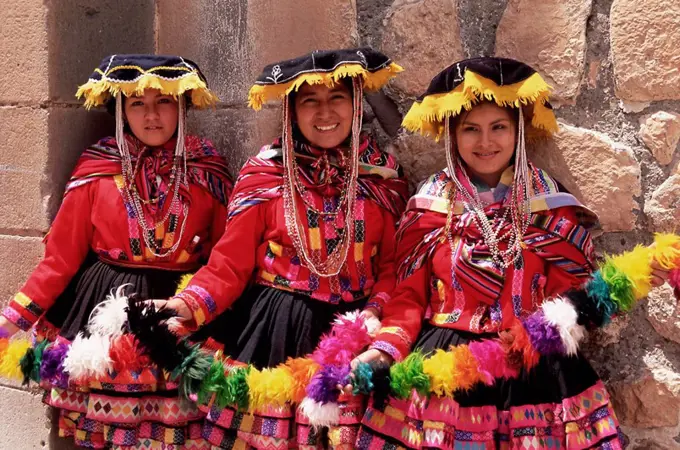 Portrait of three smiling local Peruvian girls in traditional dance dress, smiling and looking at the camera, Cuzco, Peru, South America