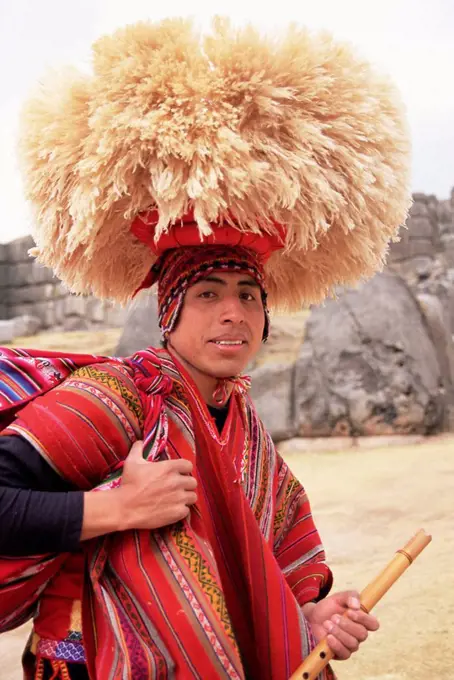 Portrait of a young Peruvian man in traditional dress, with hat and flute, Sacsayhuaman, near Cuzco, Peru, South America