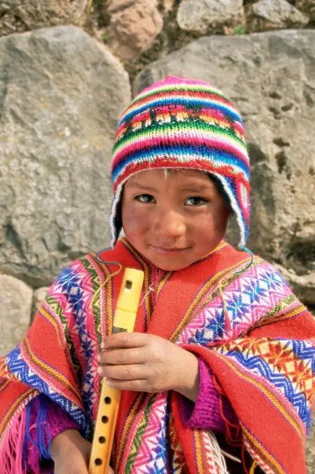 Portrait of a Peruvian boy in a knitted hat, playing the flute, near Cuzco, Peru, South America